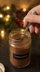 A spoon scooping cinnamon from a jar.